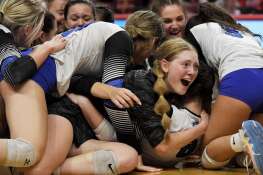 St. Francis’ Catherine D’Orazio looks out from a pile of teammates as they celebrate their victory in the Class 3A girls volleyball state championship match at Illinois State University in Normal.