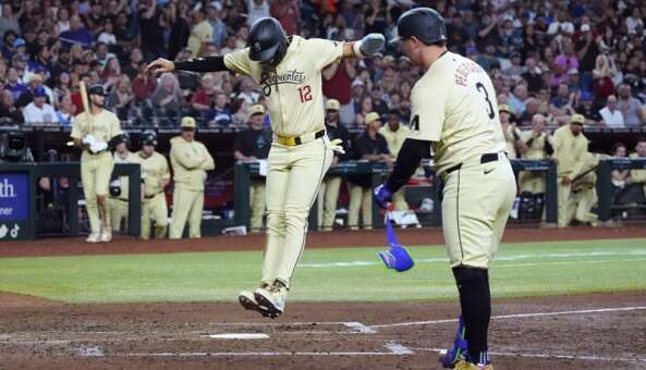 Arizona Diamondbacks' Lourdes Gurriel Jr. (12) scores on a wild pitch as Joc Pederson (3) watches on during the fifth inning of the team's baseball game against the Chicago Cubs on Tuesday, April 16, 2024, in Phoenix. (AP Photo/Ross D. Franklin)