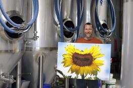 Tony Bena, owner and head brewmaster, holds a piece of art at Tonality Brewing Company Wednesday in Mundelein in preparation for the “Arts and Ales” fundraising event.