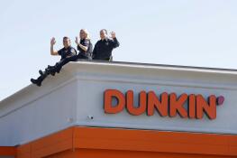 Schaumburg officer Eric Wang, from left, officer Emily Zuhr, and Lt. Elliot Rose wave to cars on Friday during the Dunkin’ Cop On a Rooftop 2024 for Special Olympics in Schaumburg.