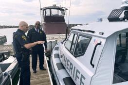 Lake County Sheriff John D. Idleburg receives a briefing from Marine Unit Sgt. Ari Briskman on a new vessel being used to patrol Lake Michigan.