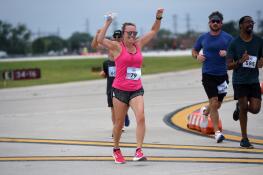 Jen Kalmus of Round Lake cheers as she makes her final approach toward the finish line during the Rock ’n’ Run the Runway 5K at Chicago Executive Airport Saturday in Wheeling.