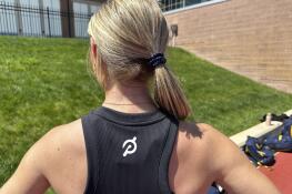 Michigan junior Riley Ammenhauser shows a Peloton logo on her shirt, Tuesday, April 30, 2024 in Ann Arbor, Mich. The Naperville native has become a record-breaking, triple-jumping track athlete and something of an entrepreneur. Leveraging her value with about 250,000 followers on social media, she has landed endorsement deals with Peloton, Gatorade and Lululemon while potentially setting herself up with a career as an influencer after hanging up her spikes. (AP Photo/Larry Lage)