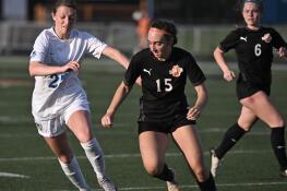 St. Charles North’s Kaitlin Glenn and Wheaton Warrenville South’s Kayla Waterman, right, chase the ball in the final second of a girls soccer game in Wheaton on Tuesday, April 16, 2024.
