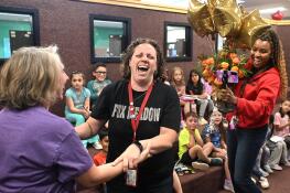 Fox Meadow Elementary kindergarten teacher Aimee Legatzke, center, is congratulated by fellow teacher Kathy Johnson on Monday after finding out she won a Golden Apple Award for Excellence in Teaching at the South Elgin school.