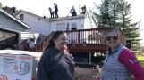 U.S. Army veteran Robin Waltrip, left, of Island Lake and Erin Gnutek chat as a crew from Feldco installs a new roof on Waltrip’s home Monday. Owens Corning donated the materials and Feldco the labor as part of the Owens Corning Roof Deployment Project to help veterans.