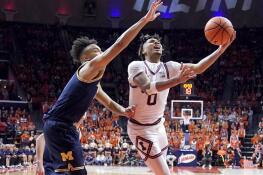 Illinois's Terrence Shannon Jr. (0) scores past Michigan's Terrance Williams II during the second half of an NCAA college basketball game Tuesday, Feb. 13, 2024, in Champaign, Ill. Illinois won 97-68. (AP Photo/Charles Rex Arbogast)