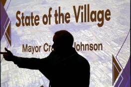Elk Grove Village Mayor Craig Johnson is silhouetted as he delivers the State of the Village address during an Elk Grove Chamber of Commerce luncheon at Belvedere Banquets on Thursday.