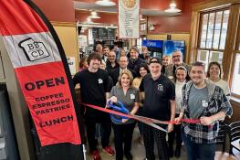 Front row, from left, owners John Plazak, Teri Plazak (holding scissors), and Chris Plazak, along with longtime employee Josh Woods, cut the ribbon celebrating the opening of the second location of Breaking Bread Catering and Deli in the Crystal Lake Train Station, 70 E. Woodstock St.