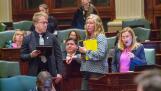 State Rep. Anna Moeller (right), D-Elgin, speaks on the House floor during debate on her bill to enact several reforms to the state’s insurance industry. The bill is an initiative of Gov. JB Pritzker, who is seated behind Moeller. The measure passed with bipartisan support.